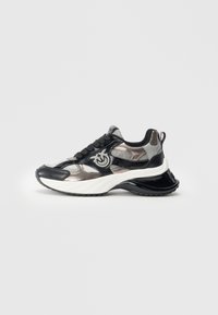 Zwarte en zilveren chunky sneaker met dikke witte zool, gestructureerde stof, zwarte veters en een lus als trekband aan de hiel.
