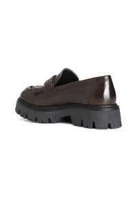 Bruna läderloafers med en kraftig svart gummisula och dekorativ hårdvara på ovansidan. Har en mjuk textur och glansig yta.