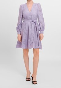 Lilac dress with a deep V-neck, structured bodice, balloon sleeves, and a tied belt at the waist, featuring a textured pattern throughout.