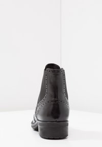 Botín negro de cuero con un acabado suave, detalles de brogue, paneles de malla y un tacón bajo apilado.