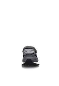 Sneaker grigia realizzata in materiali scamosciati e in rete, dotata di lacci piatti, di una strap in velcro e di una suola in gomma testurizzata. Design minimalista, vista frontale.