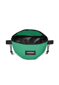 Vihreä kangasvyölaukku mustalla sisäosalla, säädettävällä hihnalla ja etupuolella Eastpak-logopatch, vetoketju osittain auki.