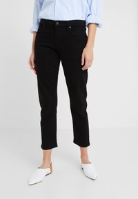 Černé džínové kalhoty po kotníky se slim fit střihem, zapínáním na knoflíky a předními kapsami. V kombinaci s bílými balerínami se špičatou špičkou.