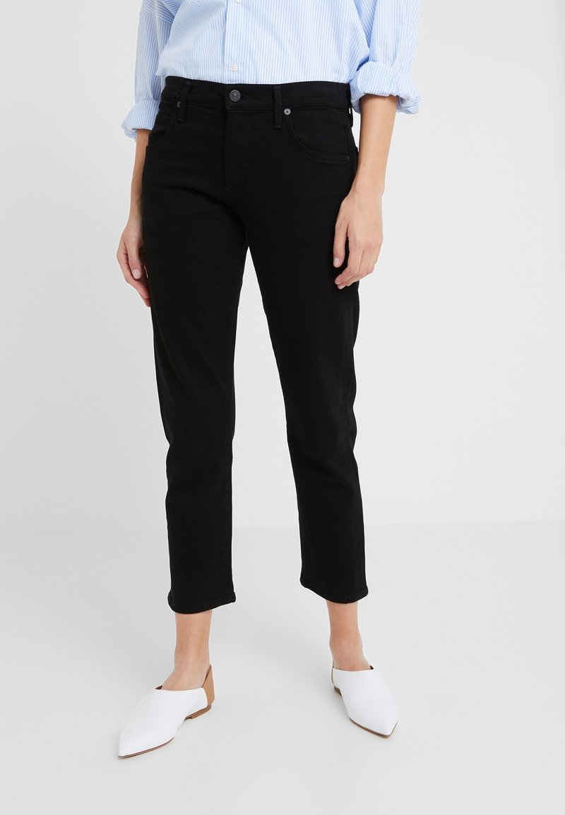 Černé džínové kalhoty po kotníky se slim fit střihem, zapínáním na knoflíky a předními kapsami. V kombinaci s bílými balerínami se špičatou špičkou.