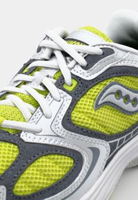 Lime green athletic shoe with gray accents, mesh upper, and white laces. Features a padded collar and a textured sole for traction.