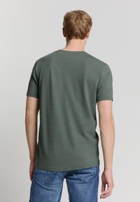 Groene T-shirt met korte mouwen, voorzien van subtiele horizontale strepen en een ronde halslijn, gemaakt van zachte katoenmixstof.