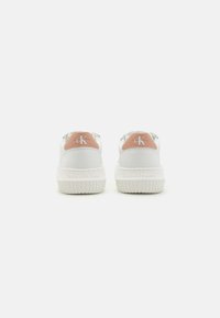 Sneakers bianchi con suola in gomma texturizzata, dettagli color pesco sul tallone e lacci argentati. Presenta il logo sul tallone e sulla linguetta.
