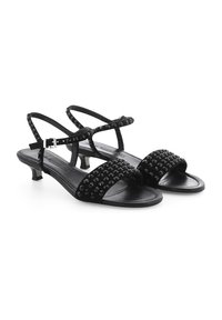 Zwarte sandalen met bandjes en een lage hak, met studs op de voorkant en een soepele leren uitstraling.