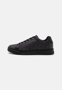 Black sneaker featuring textured leather material, tonal logo pattern, round toe, lace-up front, and rubber sole with subtle tread design.