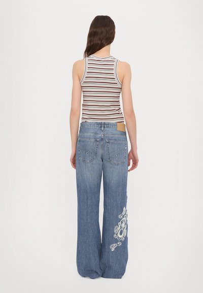 Light blue wide-leg denim jeans with white embroidered design on the left leg, paired with a brown and white striped tank top.