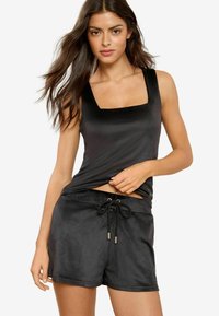 Schwarzes ärmelloses Top mit quadratischem Ausschnitt und weicher Textur, kombiniert mit schwarzen Shorts mit Kordelzug aus glattem Material.