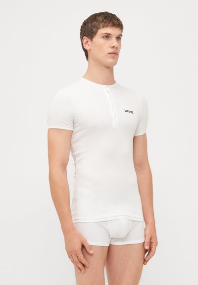 T-shirt bianco aderente a maniche corte realizzato in tessuto elasticizzato con patta a bottoni. Presenta un logo nero sulla parte sinistra del petto.