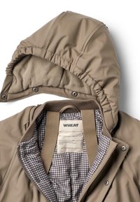 Beige waterdichte jas met een afneembare capuchon gevoerd met bruine fleece. Binnenkant heeft een geruit patroon en een waslabel. Gevoerd met drukknopen.