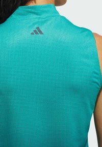 Ärmlös turkos träningsskjorta i andningsbar nätväv, med ett subtilt prickmönster och en svart Adidas-logotyp på baksidan.