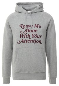 Grå luvtröja med framficka och tryckt text i mörkrött: "Lämna mig ifred med din uppmärksamhet." Mjukt material, avslappnad design.