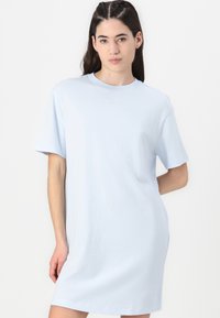 Svetlo modra bombažna oversized majica obleka s kratkimi rokavi in okroglim izrezom. Ima majhen, subtilen Nike logotip na prsih.