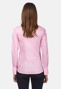 Camicia fitted rosa chiaro con maniche lunghe, cuciture laterali e polsini abbottonati, realizzata in un tessuto liscio e lucido. Nessun motivo distintivo.