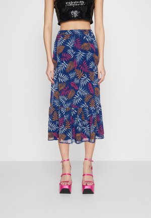 Falda midi con estampado floral en azul marino, con diseños de hojas en rosa, naranja y blanco, con un dobladillo acampanado y transparencia. Llevada con tacones de plataforma rosas.
