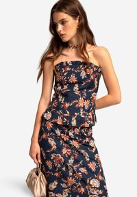 Blumen-Peplum-Oberteil aus marineblauem Stoff, mit trägerlosem Design, orange- und cremefarbene Blumenmuster, sowie einem passenden, figurbetonten Rock.