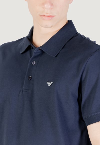 Mornarska polo majica iz mešanice bombaža, z klasičnim ovratnikom, dvema gumboma in majhnim vezenim logotipom na prsih.