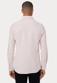 Camicia rosa chiaro a maniche lunghe con colletto classico, polsini a bottoni e orlo curvo. Fatta di un tessuto testurizzato e traspirante.