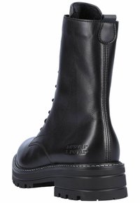 Zwarte leren enkelboot met een gestructureerde afwerking, ronde neus, vetersluiting aan de voorkant en een dikke, robuuste zool. Voorzien van een lus aan de achterkant voor makkelijk aan- en uittrekken.