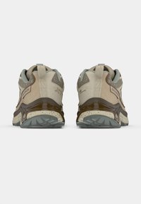 Μπεζ και καφέ παπούτσια για τρέξιμο σε μονοπάτι με υφασμ�ένο επάνω μέρος, ενισχυμένη φτέρνα και γκρι λαστιχένια σόλα, με σήμανση στο πίσω μέρος.