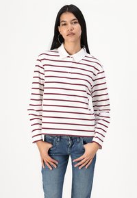 White long-sleeve polo shirt with maroon horizontal stripes, featuring a classic collar and button placket, paired with blue jeans.