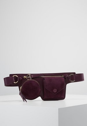 Sac banane en cuir violet foncé avec une pochette zippée ronde, une poche zippée rectangulaire et une poche à rabat avec fermeture par bouton.