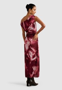 Mekko, jossa on viininpunainen ja vaaleanpunainen abstrakti kuvio, yhdistettynä olkaimeton muotoiluun ja valuväänteisiin, paritettu mustien korokepohjaisten nilkkabootsien kanssa.