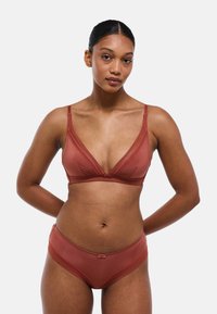 Ensemble de soutien-gorge et culotte de couleur rouille, comprenant un soutien-gorge triangulaire avec une finition lisse et de la dentelle, accompagné de culottes taille haute assorties.