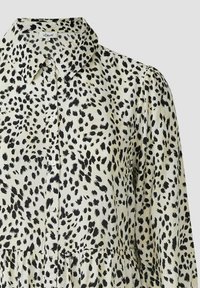 Camicia button-up con un design animale in nero e beige. Presenta un colletto classico, tessuto testurizzato e maniche a sbuffo.