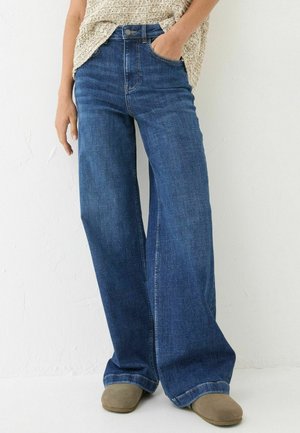Weite Denim-Jeans in Dunkelblau. Mit hoher Taille, Fünf-Taschen-Design und subtilen Abnutzungserscheinungen. Genähte Säume, glatte Textur.