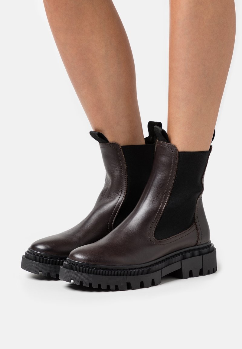 Brown leather ankle boots with elastic side panels, textured rubber sole, and pull tabs. Rounded toe and sturdy, chunky heel.