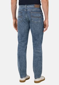 Modre jeans s ravnimi hlačnicami, petimi žepnimi stili, rjavim usnjenim všitkom na pasu in diskretno zbledelim videzom.