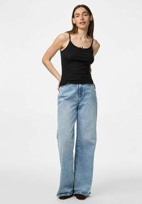 Débardeur noir à côtes avec des bretelles fines, associé à un jean ample bleu clair, doté d'un design classique à cinq poches et d'un léger délavage.