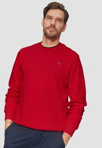 Rode sweatshirt met een ronde hals en lange mouwen. Heeft een klein logo in donkere print op de borst. Gladde katoenen stof.