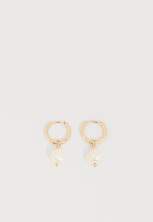 Boucles d’oreilles créoles en or avec des perles blanches irrégulières pendantes, présentées sur un fond clair uni.