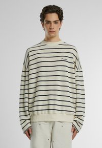 Maglione a righe; base crema con righe orizzontali blu navy, scollatura rotonda, vestibilità relaxed, polsini e orlo a costine, dettaglio logo ricamato.