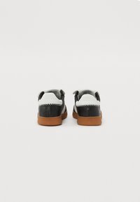 Sneaker mit einem Obermaterial aus schwarzem Leder, weißen Akzenten und einer Sohle aus Gummi. Verfügt über eine glatte Textur und kontrastierende Nahtdetails.
