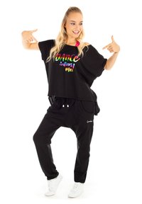 Crna oversized majica s veseljem "DANCE defines me!"; uparena s crnim trenirkama s bijelim logoom; bijele tenisice.