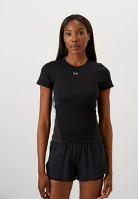 Camisola atlética justa preta com mangas curtas, lados texturizados e um pequeno logótipo no peito. Combinada com calções atléticos pretos.