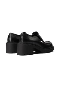 Scarpe platform in pelle nera con punta arrotondata, tacco largo e suola strutturata. Presentano un design caratteristico a taglio e una finitura elegante.