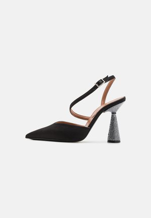 Zapato de tacón alto negro con tira en el tobillo, punta afilada, tejido de satén y un tacón cónico texturizado decorado con cristales. Correa ajustable en el tobillo.