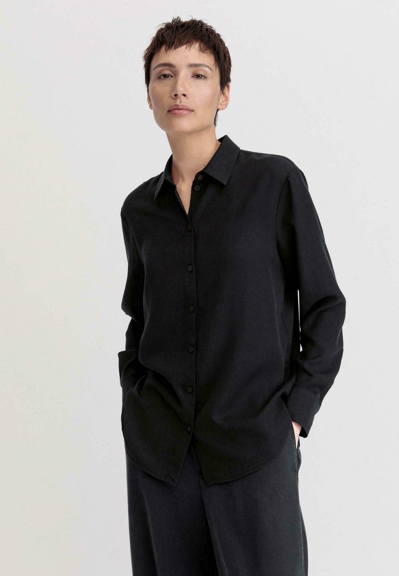 Black button-up shirt with long sleeves, featuring a smooth texture, a collar, and a relaxed fit, paired with matching pants.