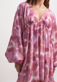 Abito fluido realizzato in tessuto leggero, con scollatura a V, vita elastica e un motivo floreale astratto rosa, arricchito da maniche ampie.