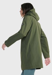 Giacca impermeabile verde oliva con cappuccio, con un logo sulla manica sinistra, maniche lunghe, taglio dritto e design minimalista.