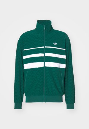 Jachetă verde din fleece cu guler înalt, închidere cu fermoar și dungi orizontale albe pe piept. Are un material texturat și buzunare laterale.