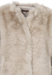 Cappotto in pelliccia sintetica di un beige chiaro con una texture morbida e soffice. Presenta un collo rotondo e nessun chiusura o dettaglio visibile.