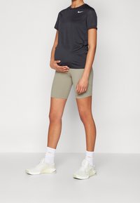 Musta lyhythihainen Nike-t-paita, oliivinvihreät istuvat shortsit, valkoiset lenkkarit, valkoiset sukat. Yksinkertainen, urheilullinen muotoilu, sileä kangaspinta.